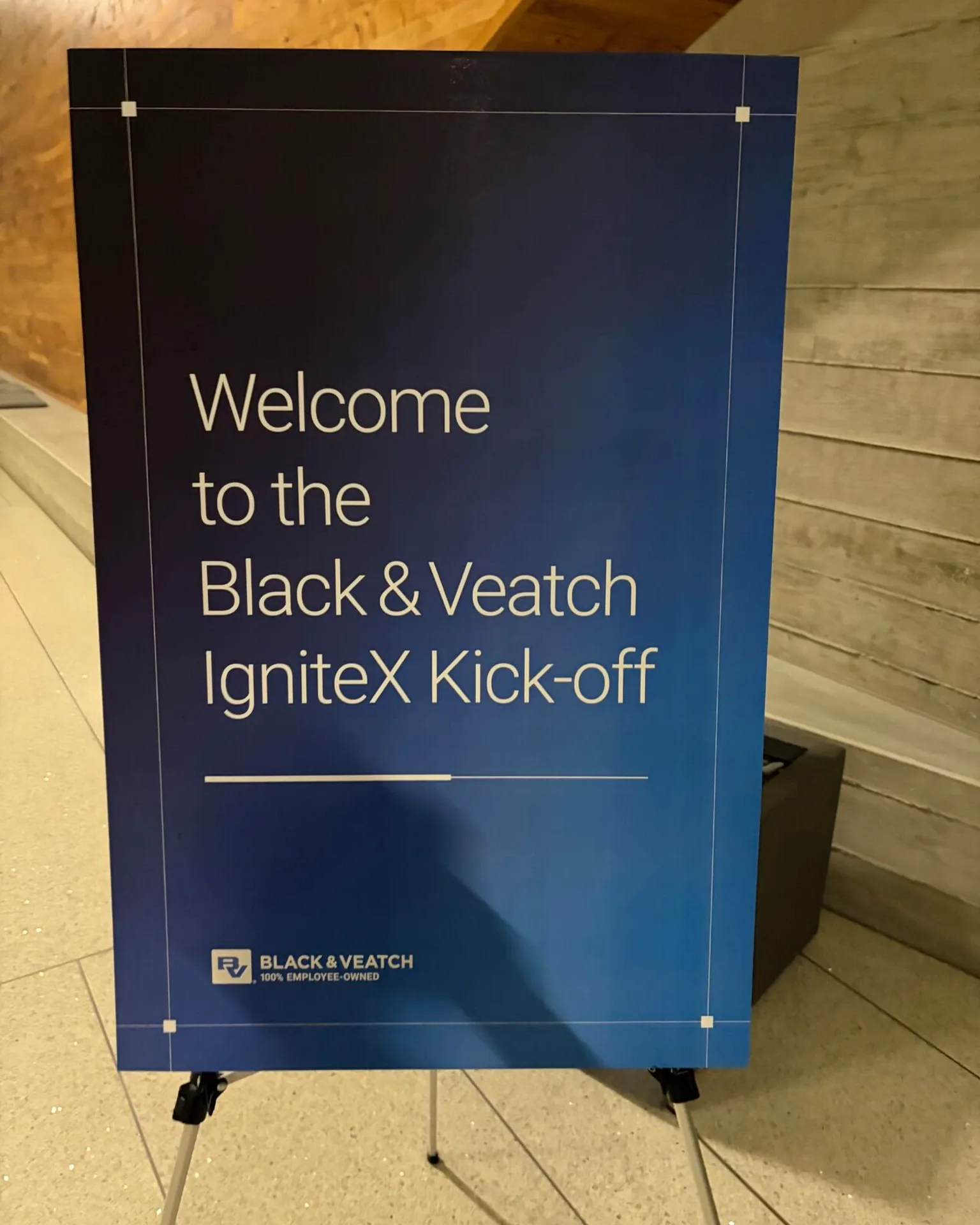 A blue lobby sign on an easel reading Welcome to the Black and Veatch IgniteX Kick-off, with the Black and Veatch 100 percent employee-owned logo at the base